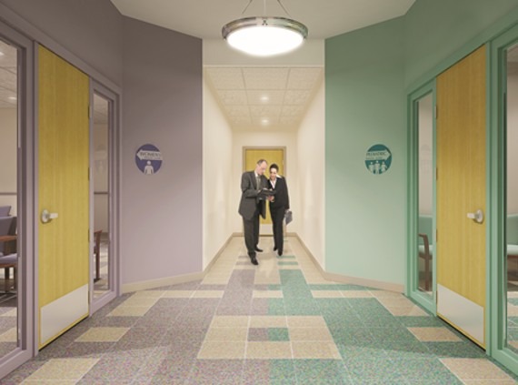 Two men in suits engage in conversation while walking down a brightly colored hallway lined with labeled doors, suggesting a professional setting.